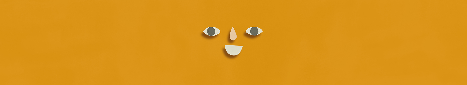 Paper cut shapes arranged in a smiling face on a dark yellow background